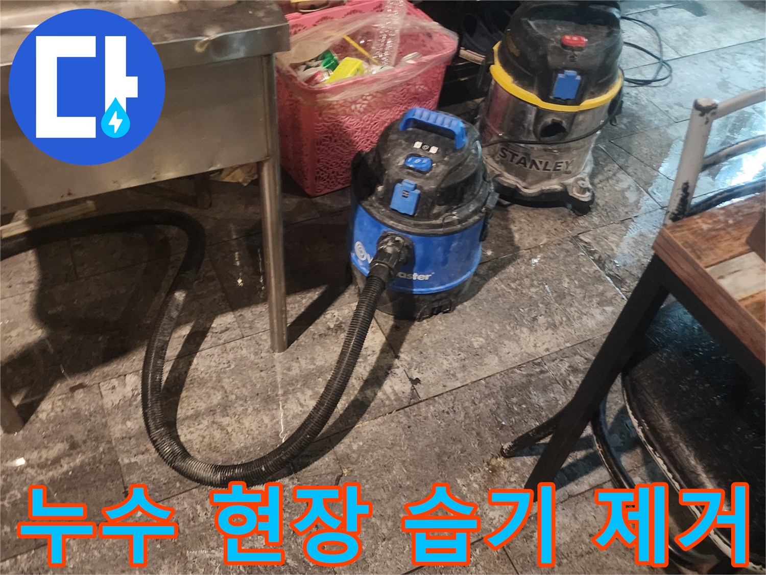 누수 피해 현장에서-바닥에 고인 물을-신속하게 제거하고-건조시키기 위해-사용되는-전문 석션 장비 두 대가-작업 준비를 마친 모습입니다.