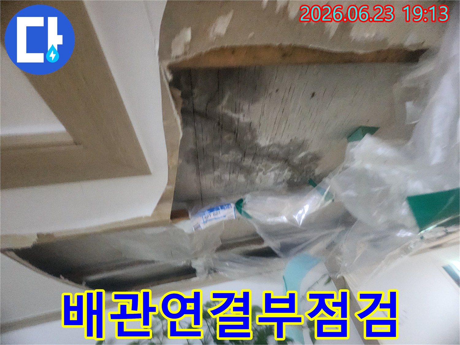 천장 내부의 배관 연결 부위를-면밀히 점검하여-누수 발생 여부를 확인하는-전문가의 모습입니다
