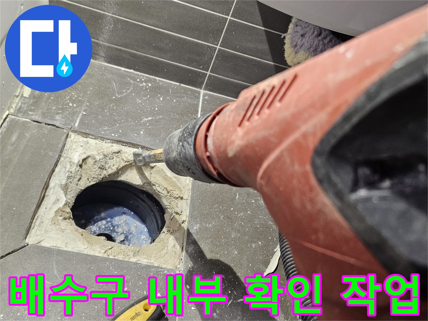 드릴로 뚫어낸 타일 사이 배수관 입구가 보이는 현장 사진