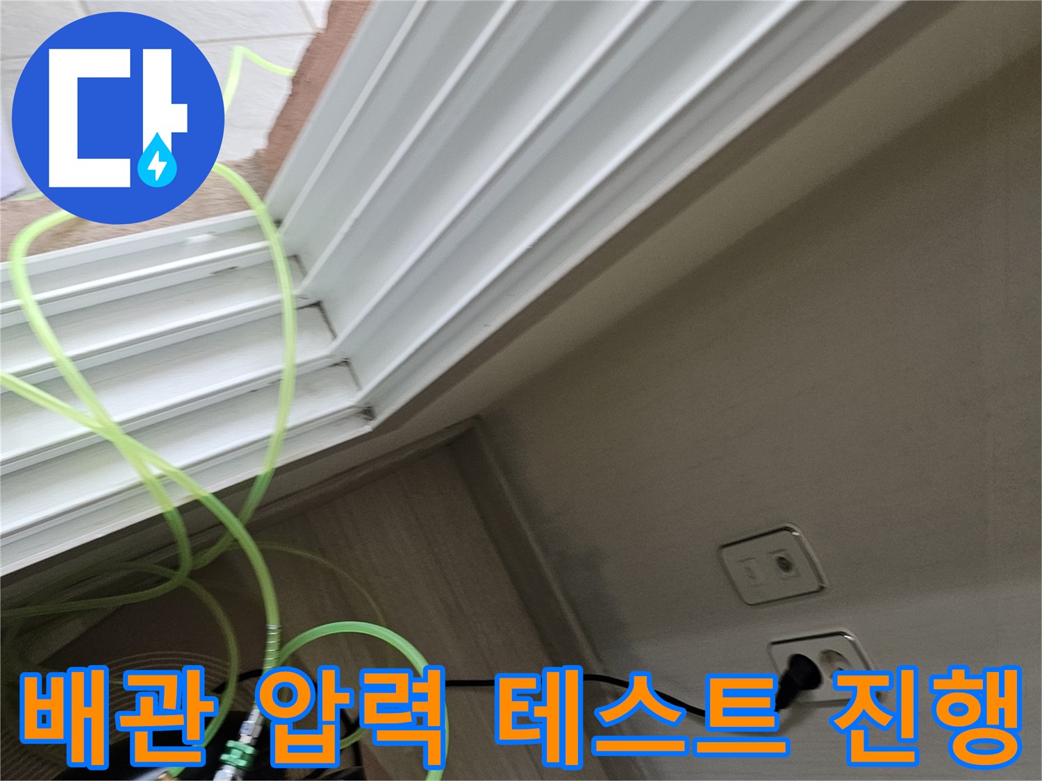 콘센트 옆 벽면 배관에 연결된 공압 테스트 장비와 호스