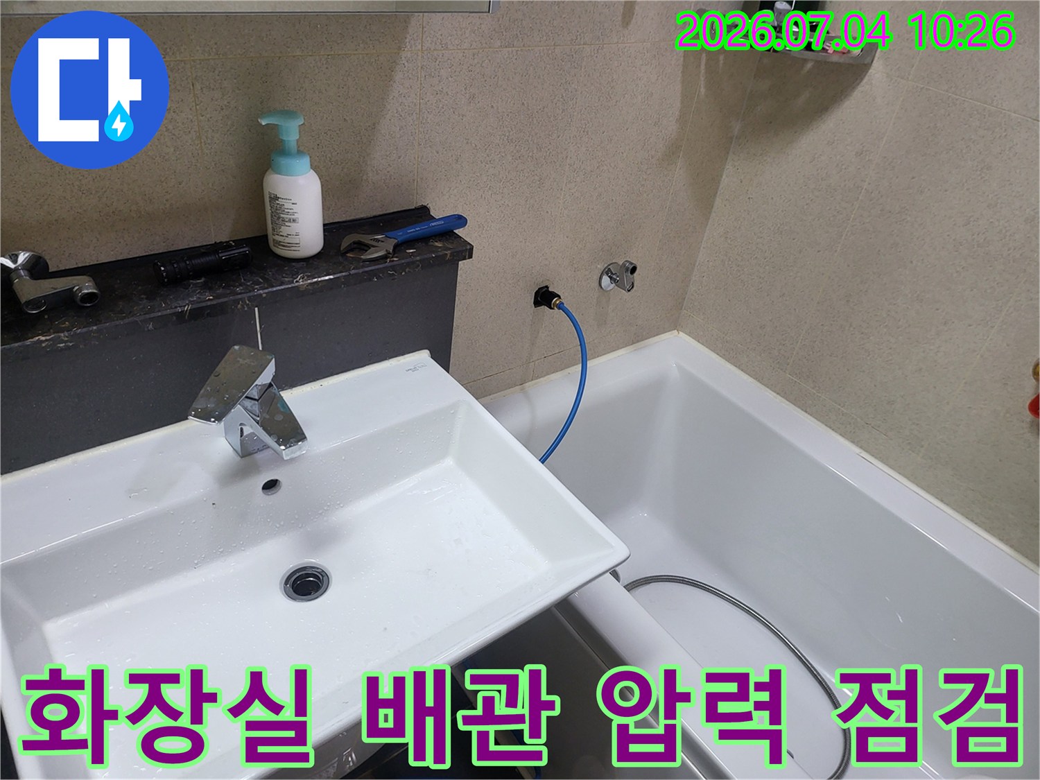 화장실 세면대 옆 수도 배관에 연결된 호스와 매니폴드 장비를 활용한 누수 정밀 점검 현장