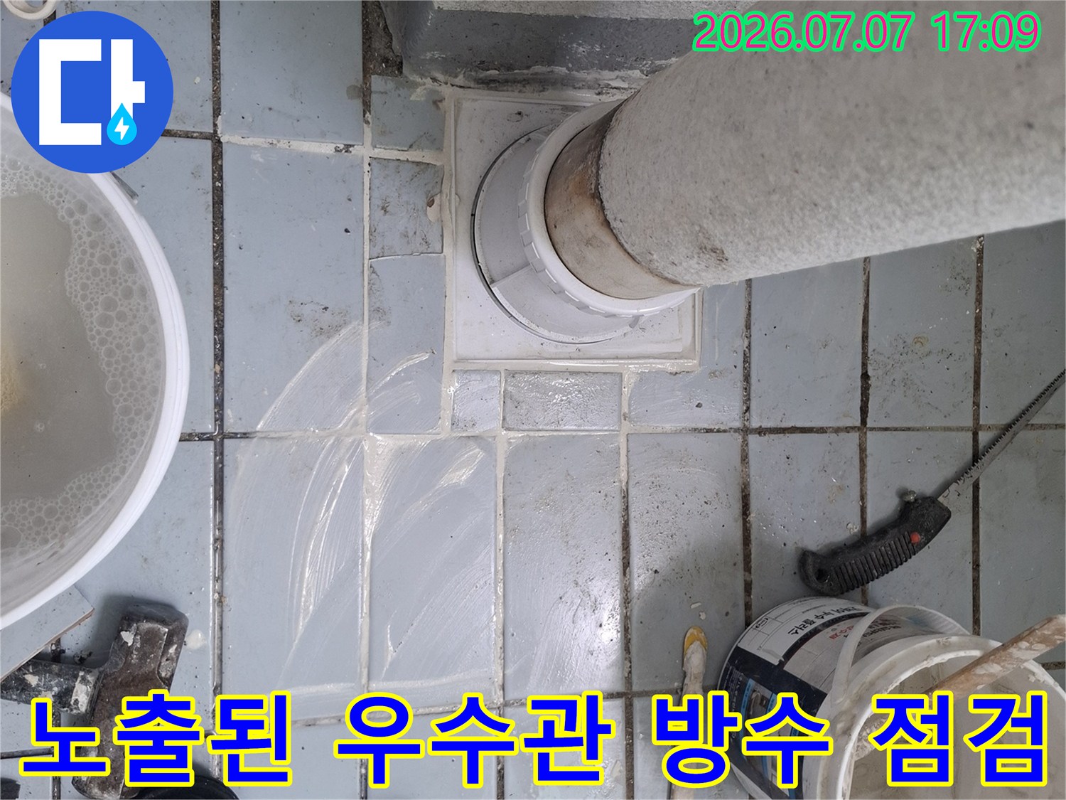 작업용 버킷과 고무장갑이 놓인 우수관 주변 누수 보수 현장 사진