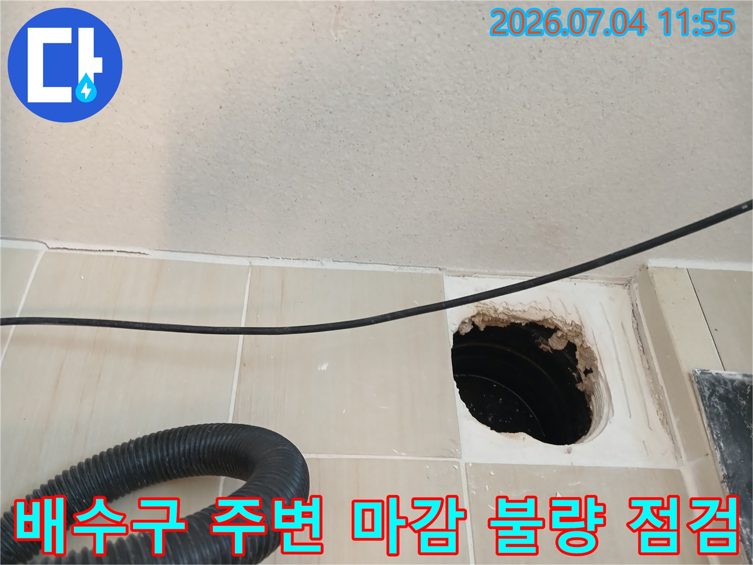 타일 사이로 노출된 배수관과 파손된 주변부의 상태를 촬영한 사진