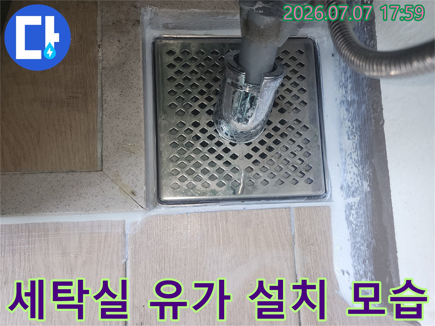 세탁실 바닥에 고정된 금속 재질의 배수구 유가와 연결된 세탁기 배수 호스