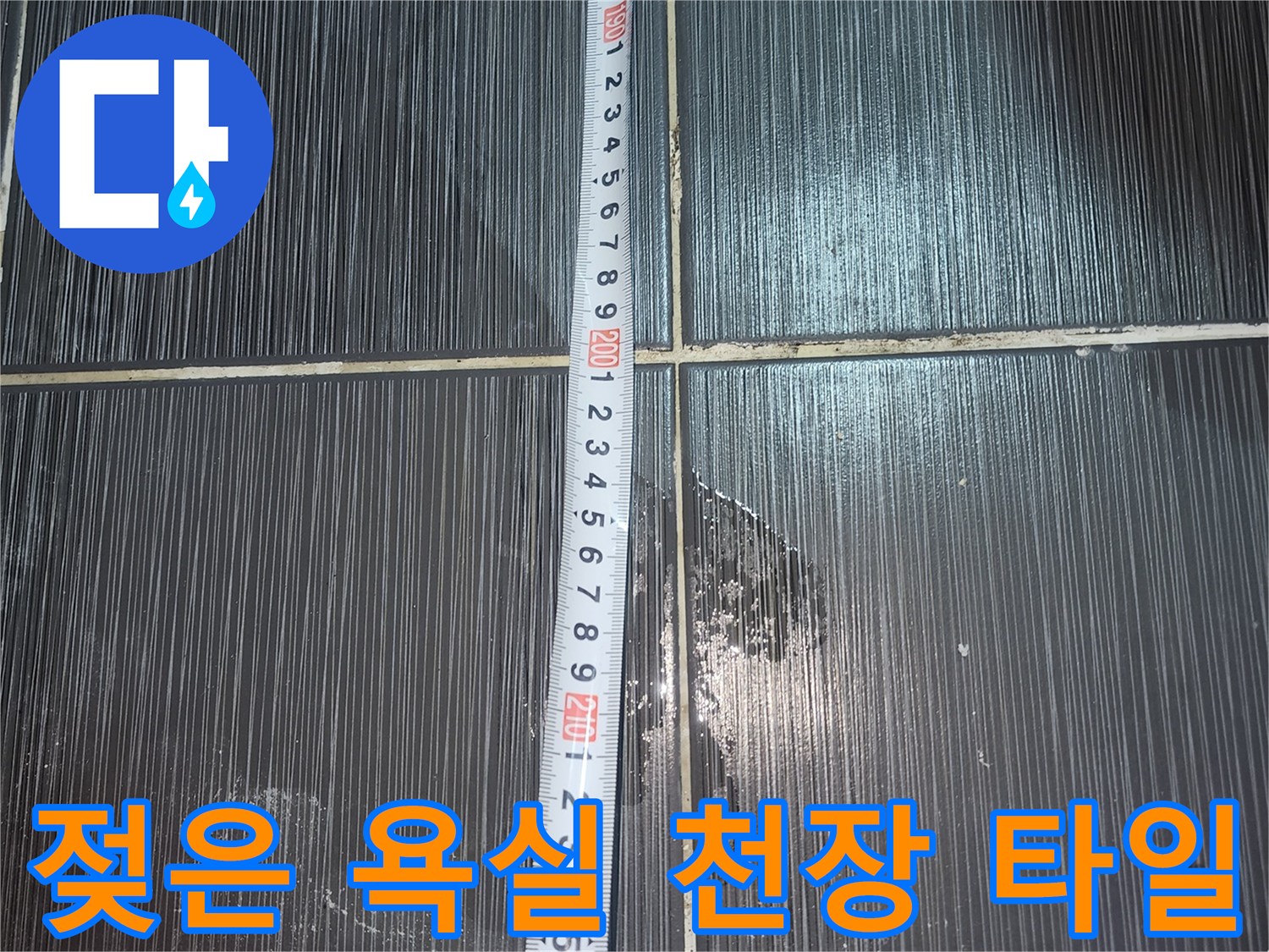 줄자를 대고 누수 오염된 화장실 천장 타일을 촬영한 사진