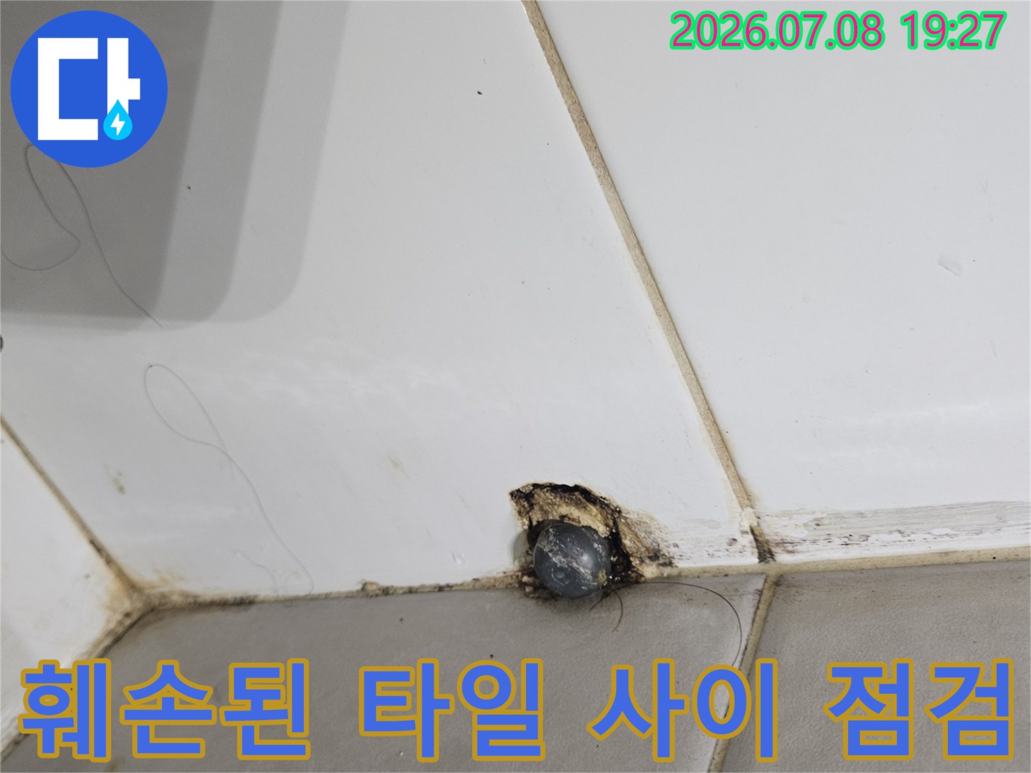 갈라지고 파손된 흰색 타일과 배관 연결 부위의 정밀 진단 모습