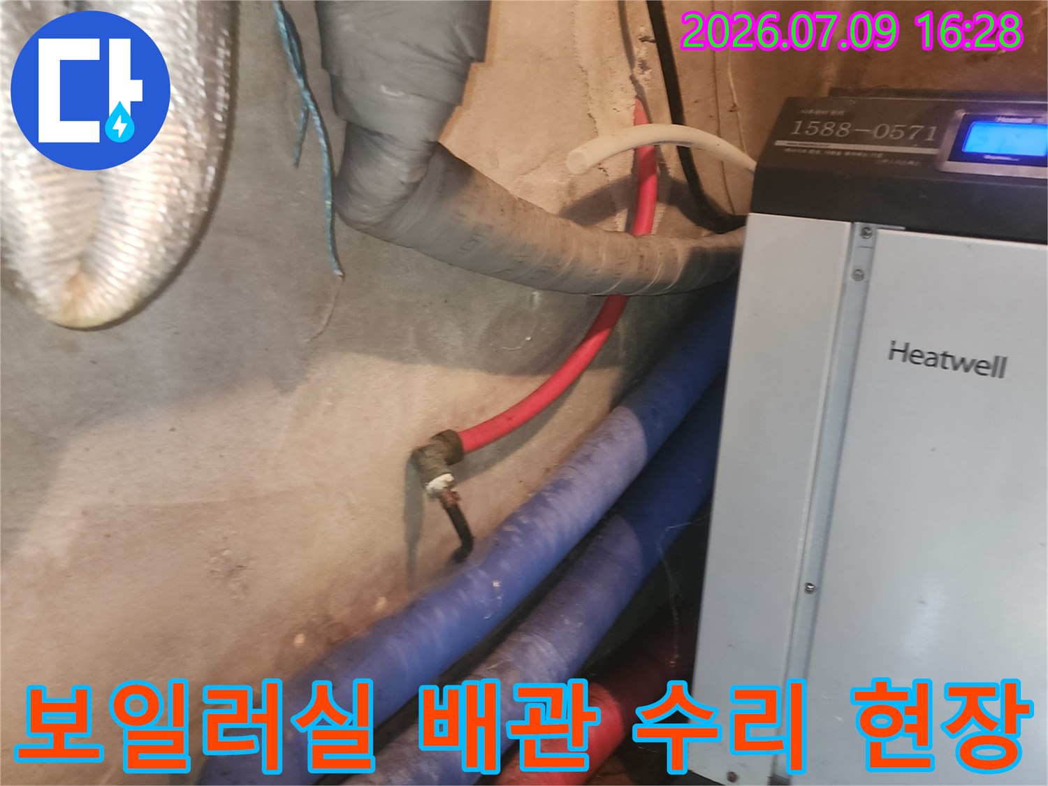 보일러기계 옆에 위치한 다양한 색상의 노출 배관과 단열재가 감싸진 배관 구조