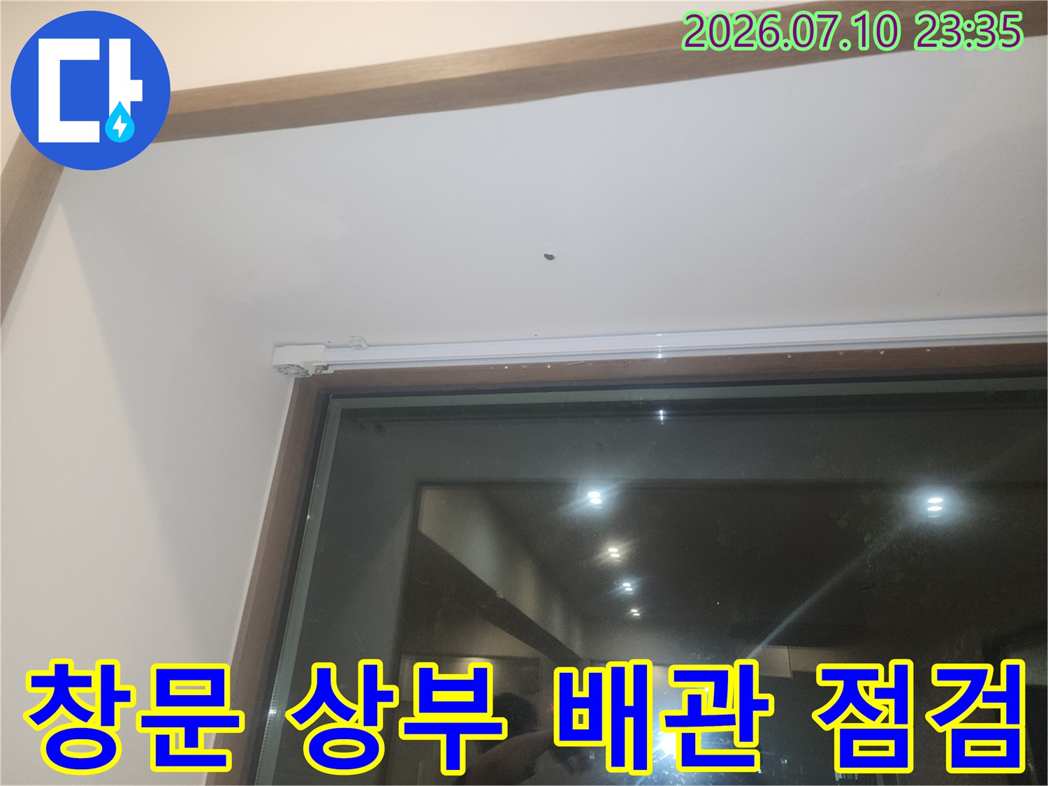 천장 마감과 창틀 사이의 좁은 공간에 위치한 배관 상태를 세심하게 체크하는 모습