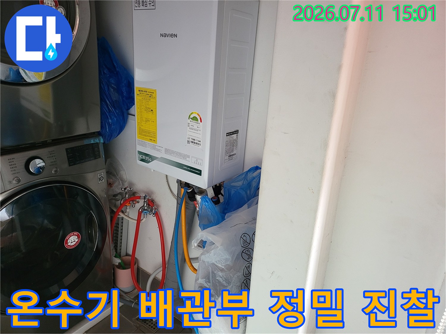 노란색과 파란색 배관이 연결된 온수기 하단부를 꼼꼼하게 점검하는 모습