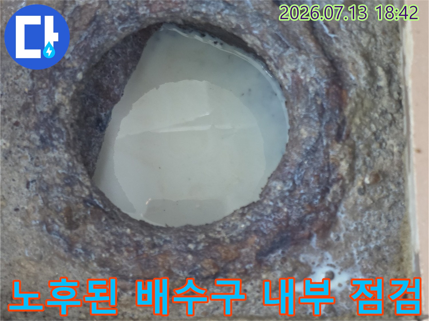 부식된 콘크리트와 노출된 내부 구조를 가진 세탁실 배수구