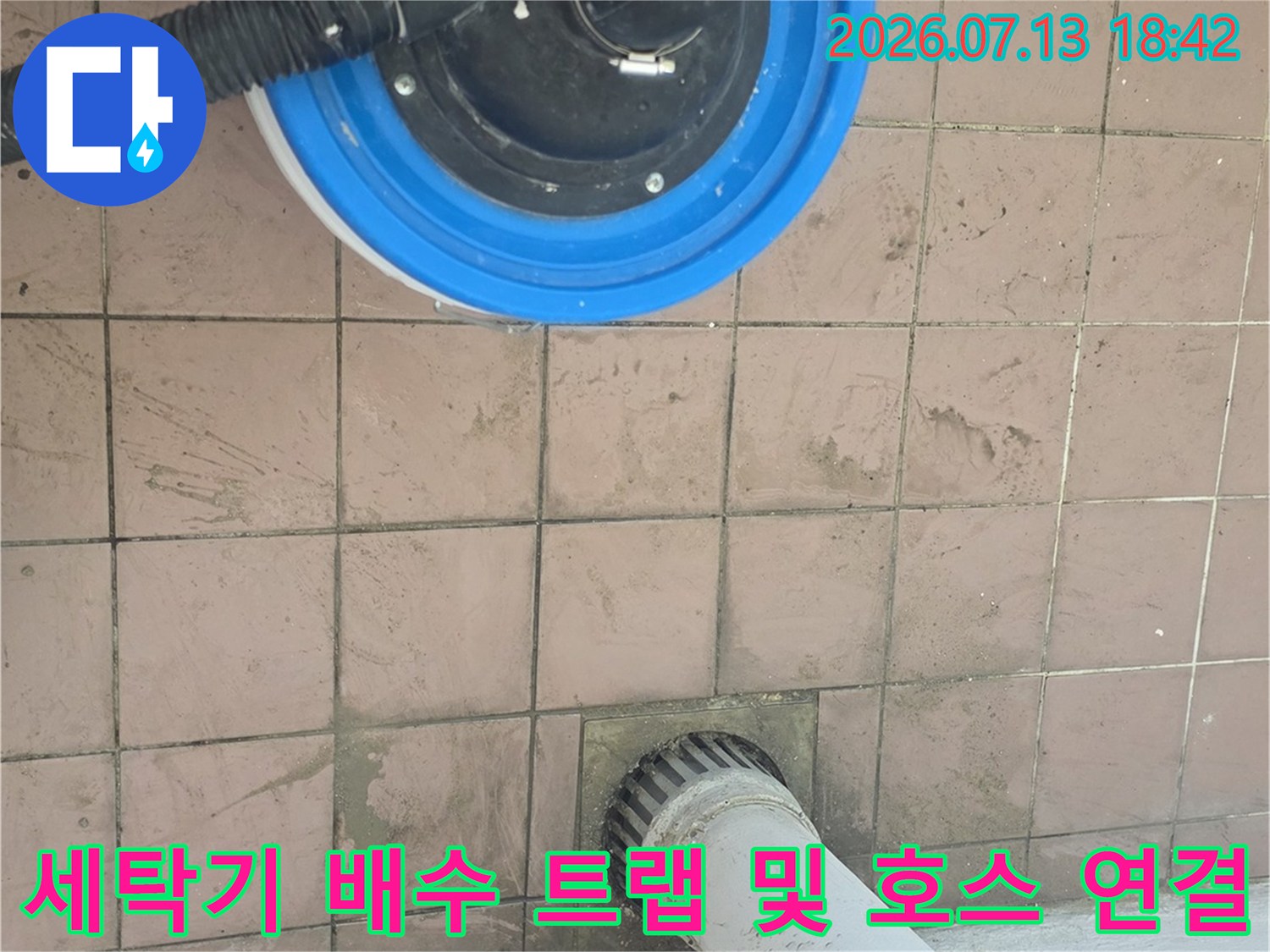 파란색 도색이 된 배수용 트럼에 고정된 세탁기 배출용 호스