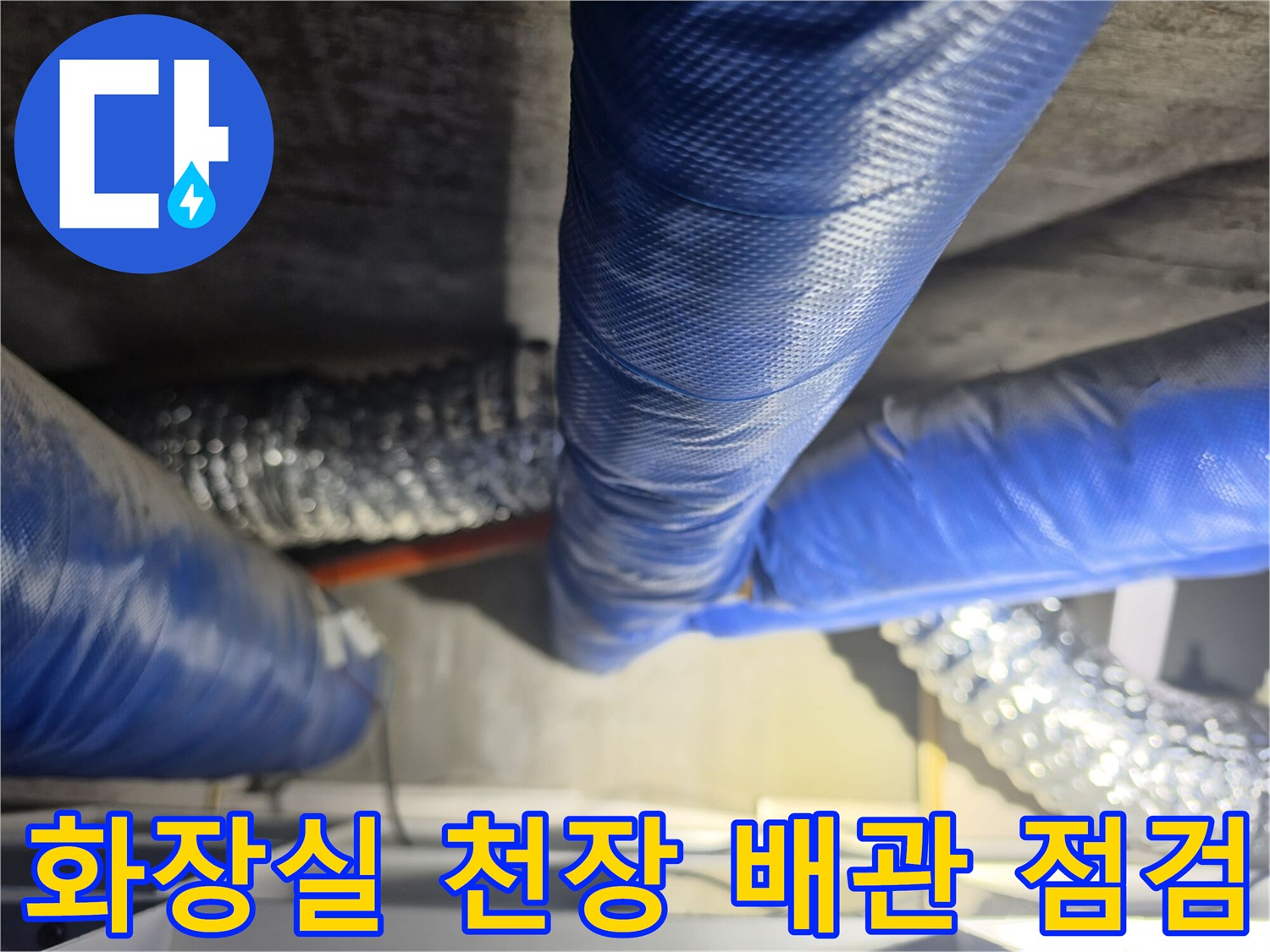 파란색 보온재로 감싸진 배관과 은색 자바라 호스가 설치된 화장실 천장 내부 모습