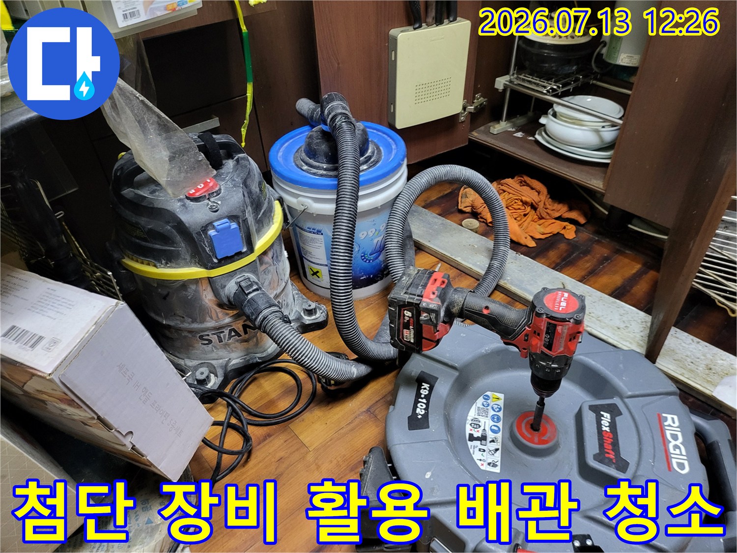 석션기와 내시경 카메라를 사용하여 싱크대 하단 배수관 내부의 이물질을 제거하고 점검하는 장면