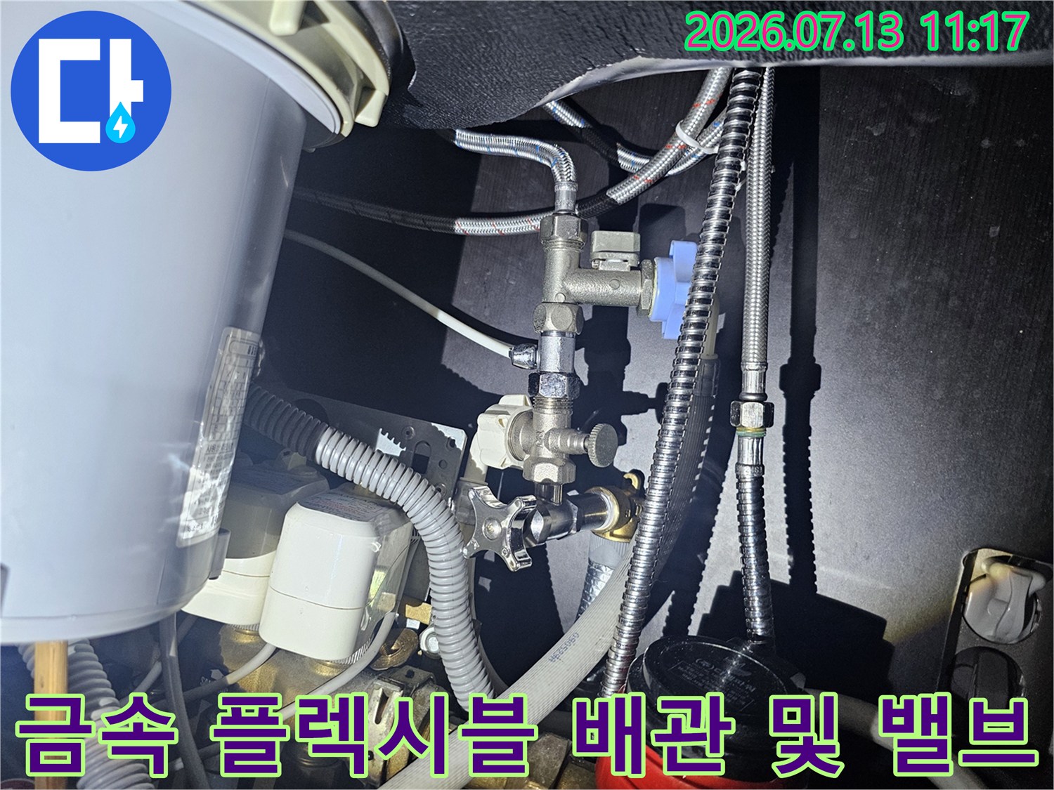 은색 금속 배관과 파란색 손잡이가 달린 밸브가 설치된 보일러 하단부