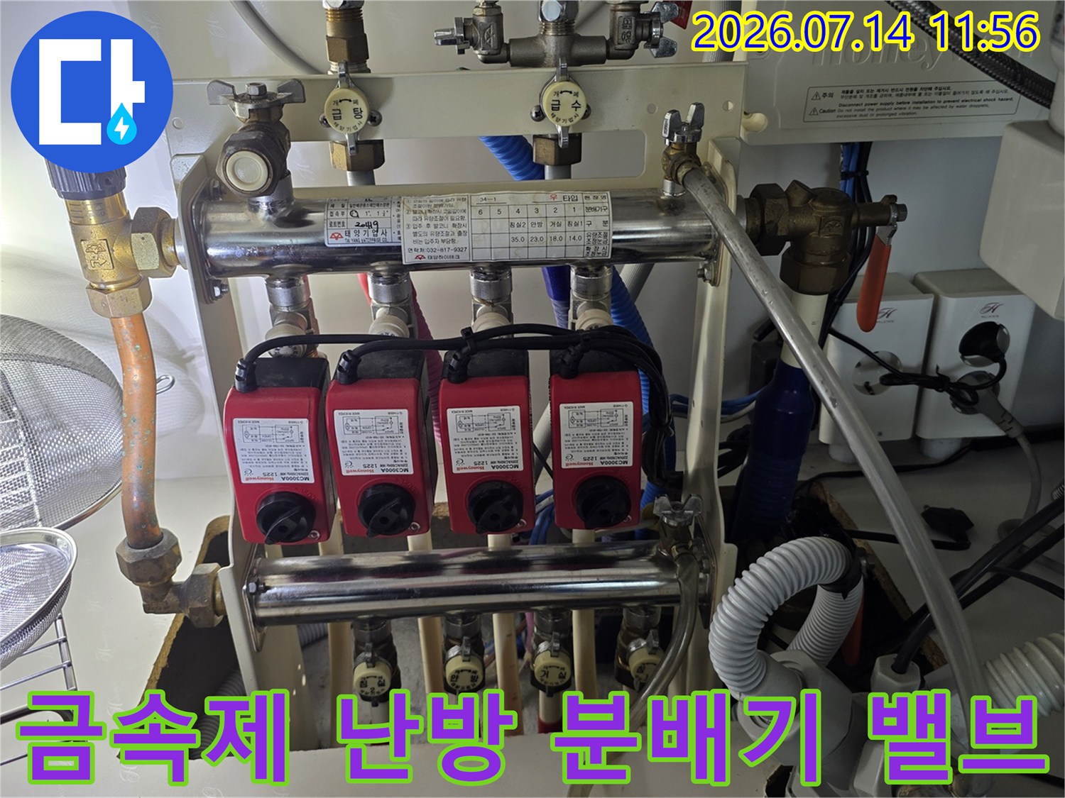 붉은색 조절 밸브가 장착된 보일러 분배기와 구리 배관-연결 부위 상세 사진