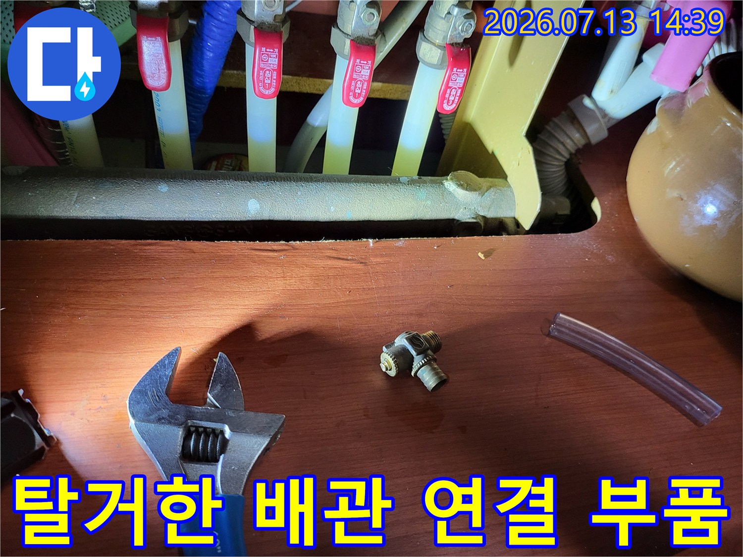 누수가 발생하여 제거된 황동 소재의 티자형 배관 조인트와 작업 도구