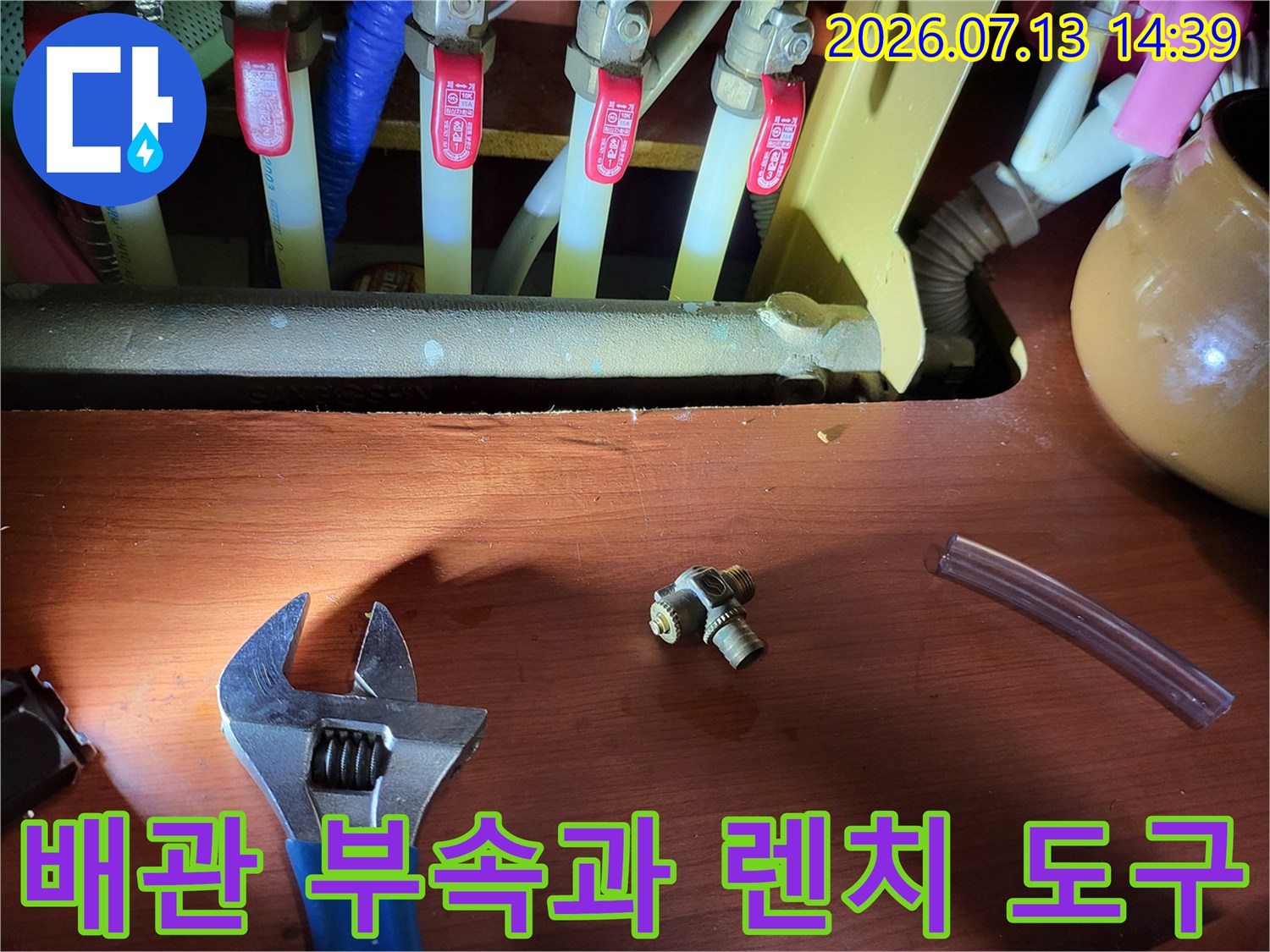 분배기에서 분리한 황동색 티자형 연결 부품과 몽키스패너가 나란히 놓인 모습