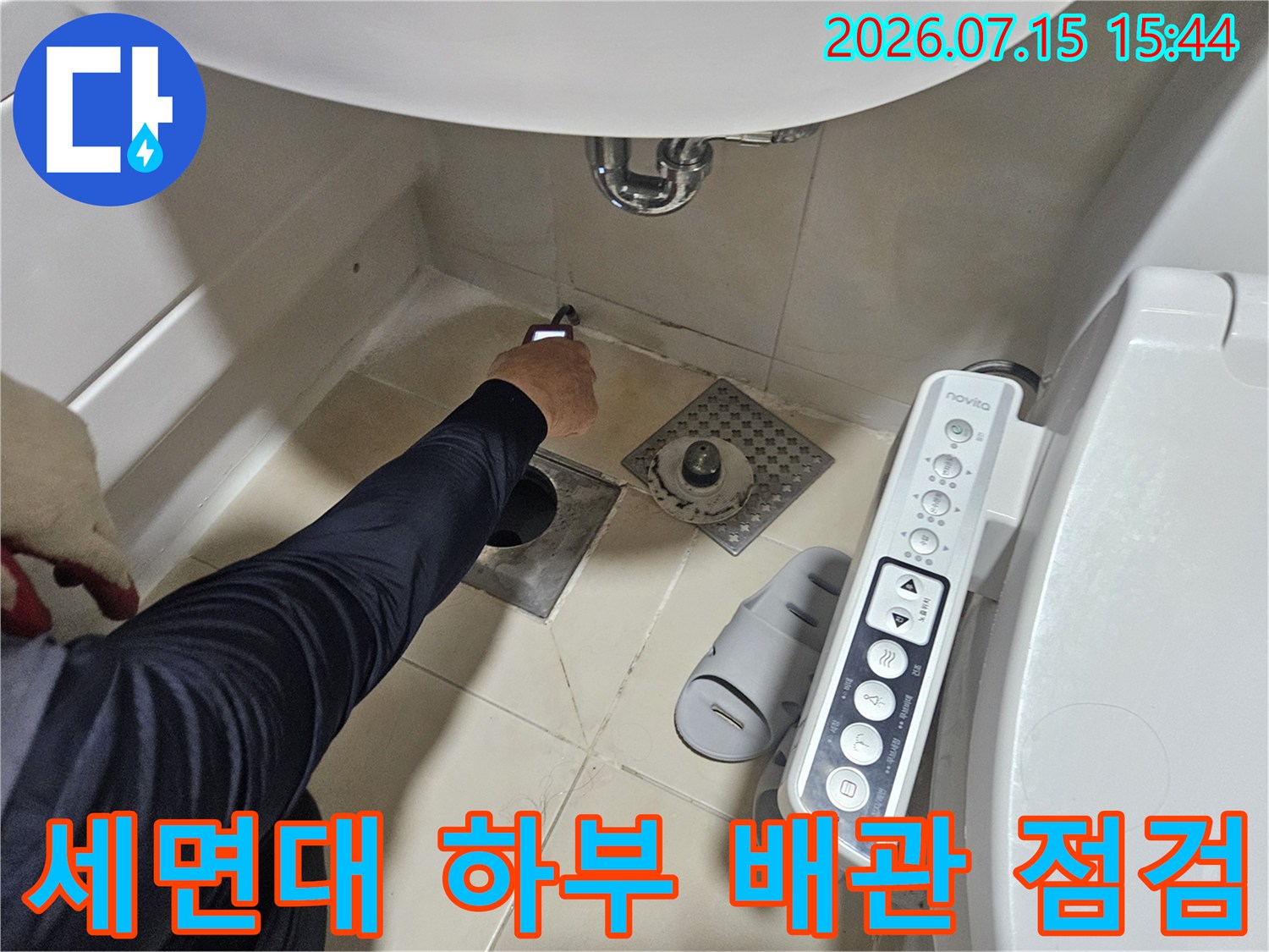 세면대 아래쪽 배관 연결 부위를 점검하는 누수 탐지 장비와 작업자의 손