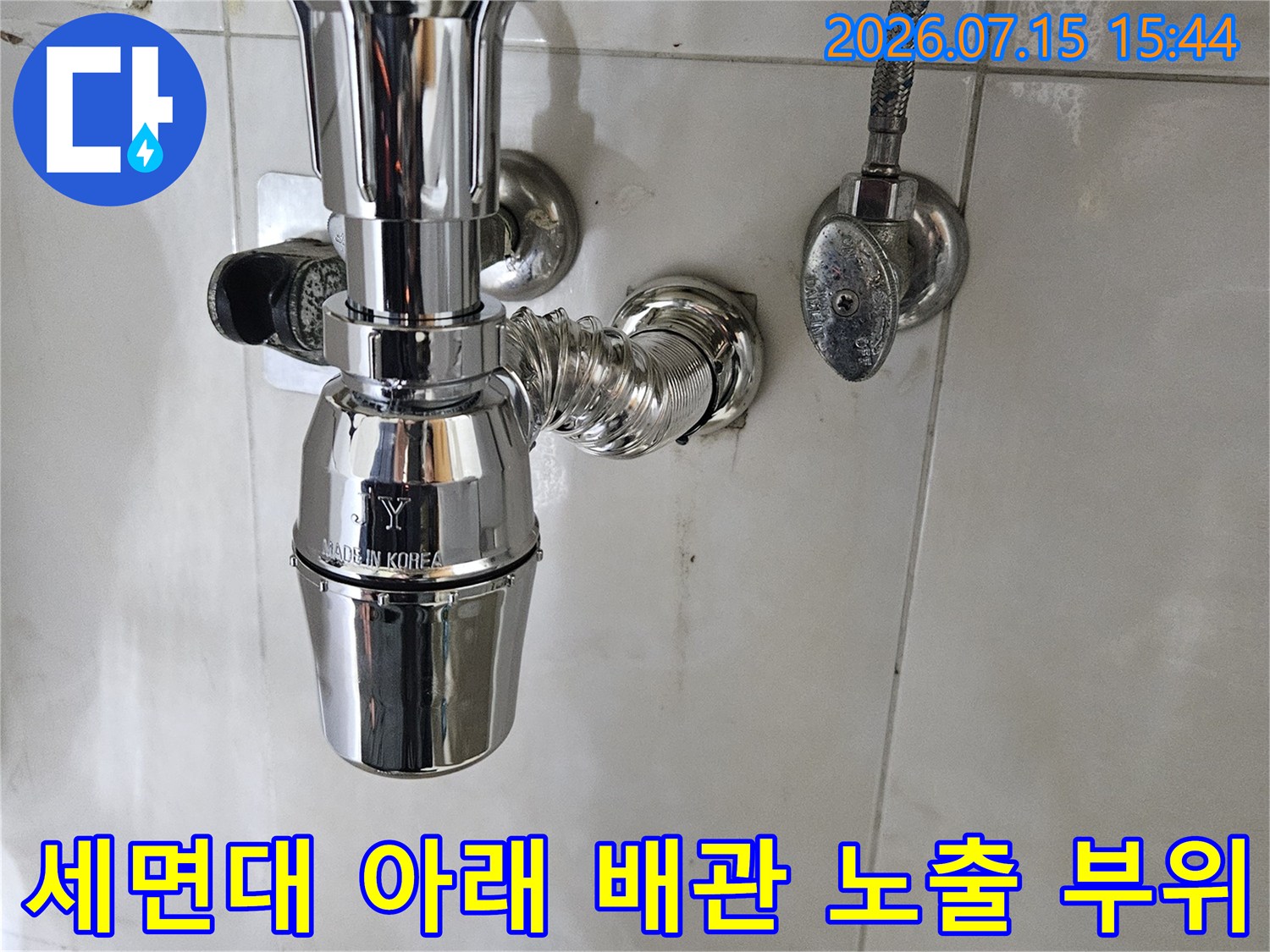 세면대 하단에 위치한 은색 금속제 굴곡 배관과 연결부의 상세도