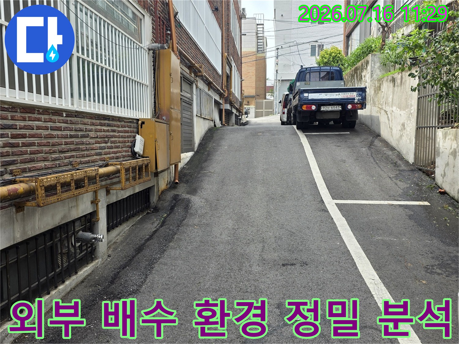 상가 건물 외부 노면에 위치한 우수관과 지면의 접촉 상태를 점검하는 모습입니다.
