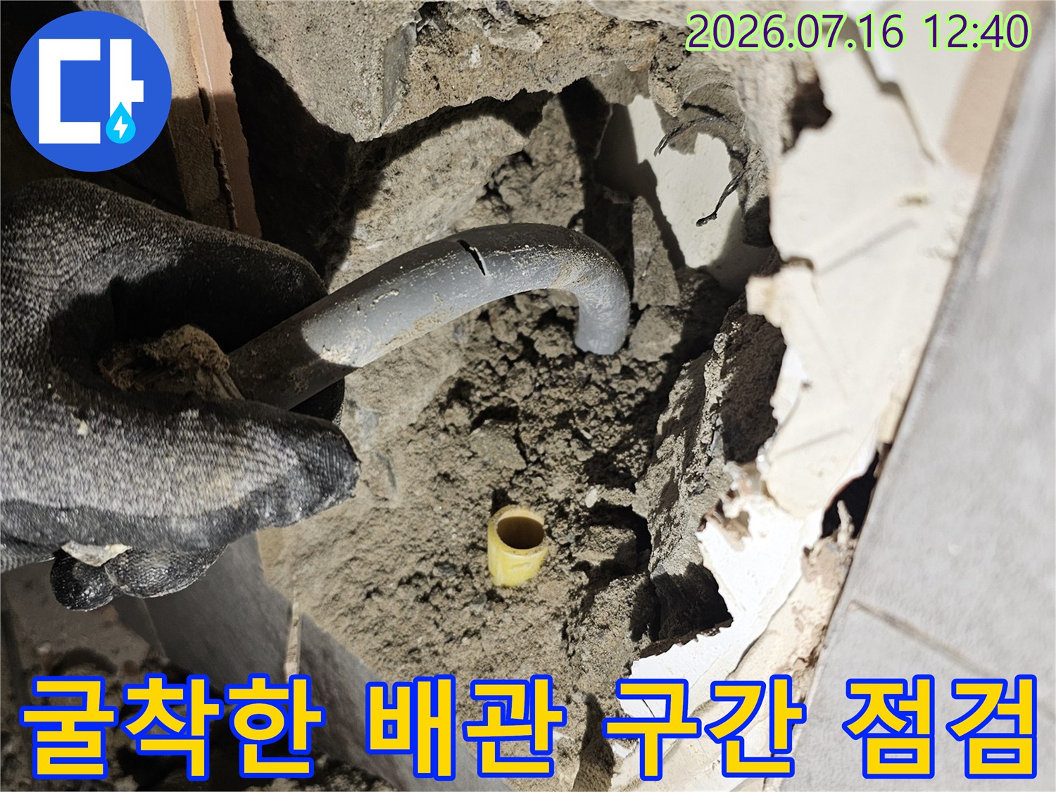 벽면을 파헤친 후 나타난 배관 주변의 토사와 시멘트 덩어리를 확인하는 공사 현장