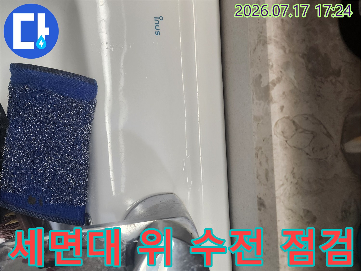 흰색 세면대 위에 올려진 파란색 수세미와 크롬 재질의 수도꼭지
