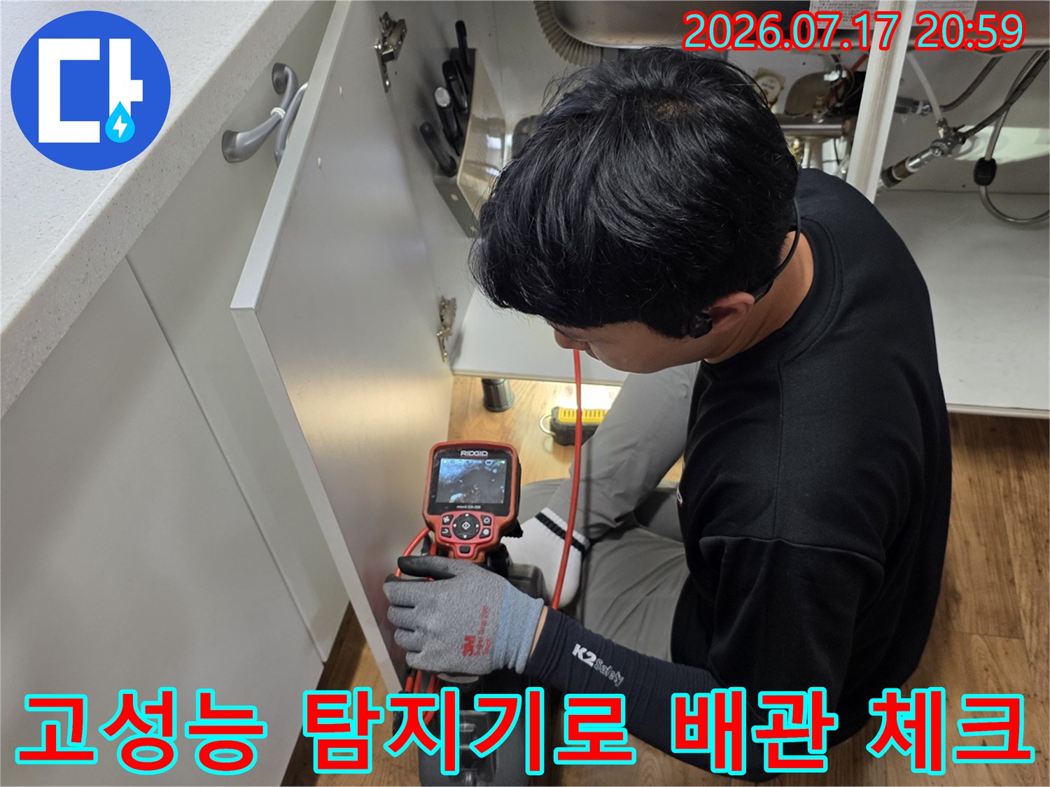 전문가가 싱크대 하단부에 위치한 배관을 정밀 탐지 장치로 꼼꼼하게 스캔하는 모습