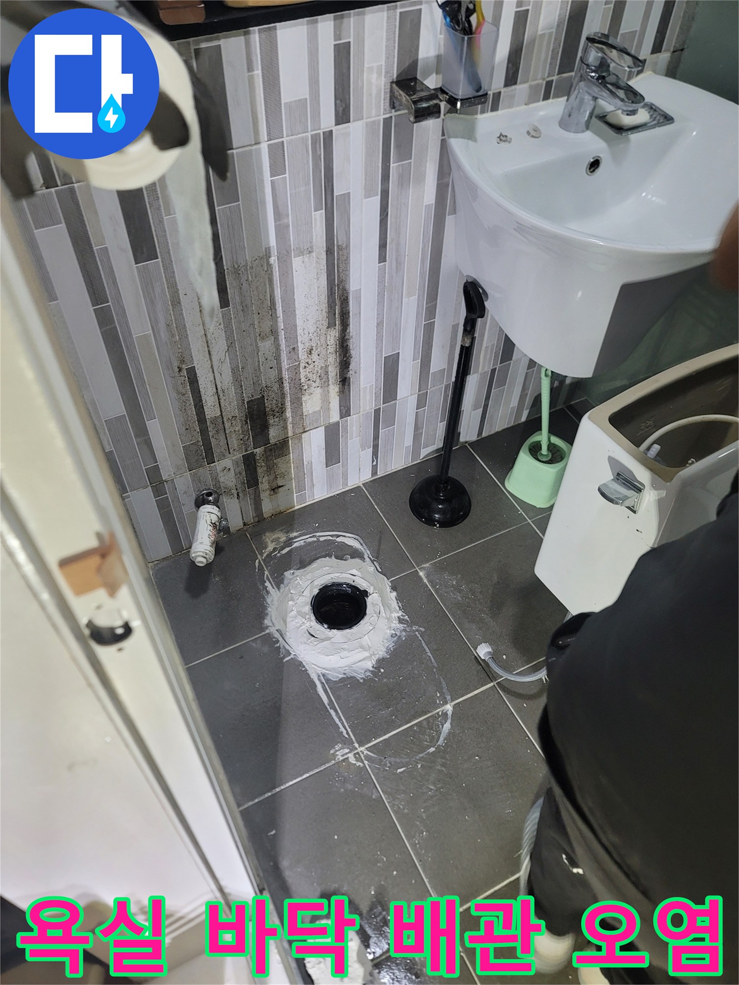 변기 하단 배수구 주변의 젖은 타일과 벽면의 얼룩진 상태를 촬영한 사진