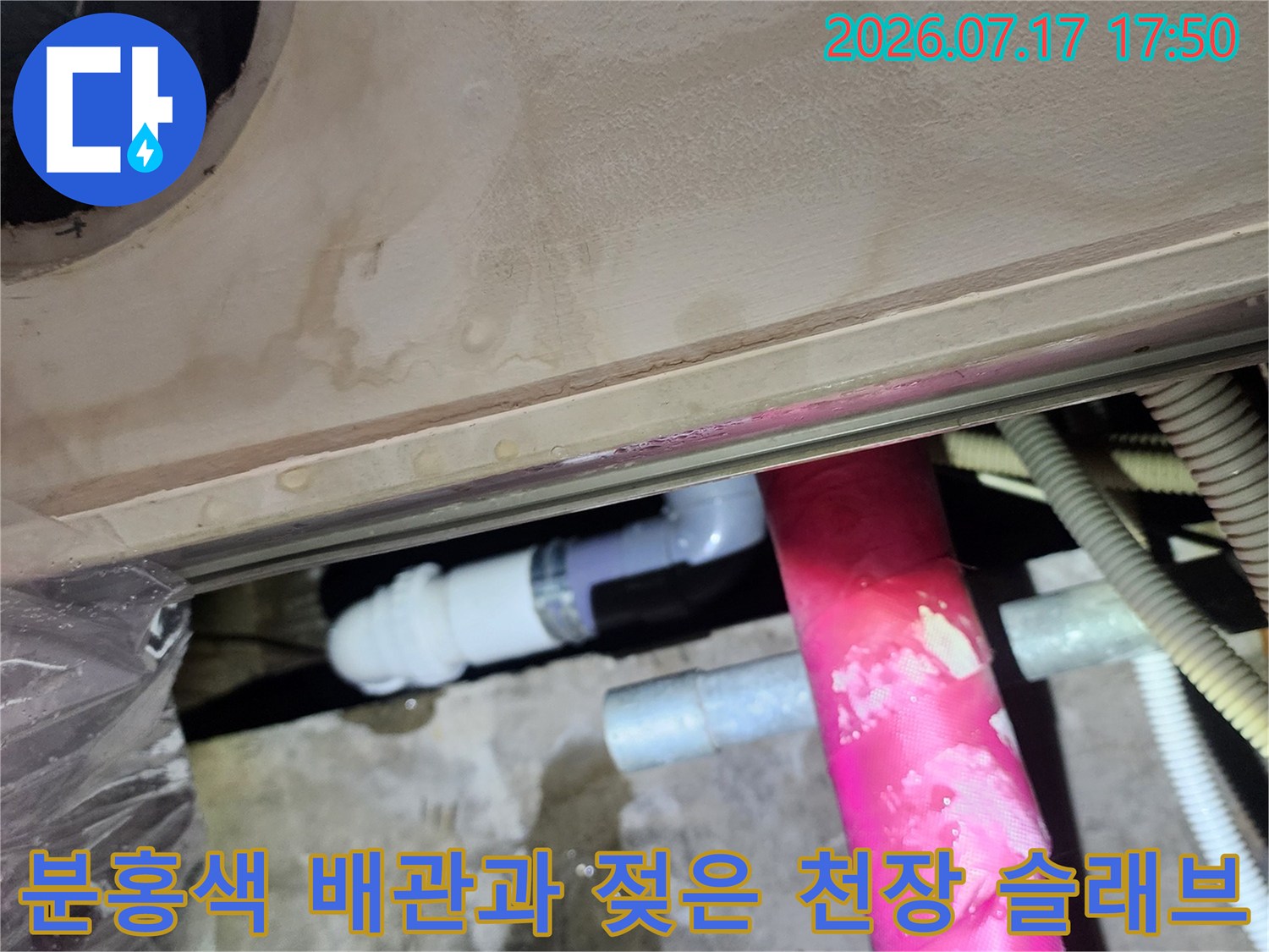 물에-젖어-얼룩진-콘크리트-천장과-그-위에-설치된-분홍색-보온-배관