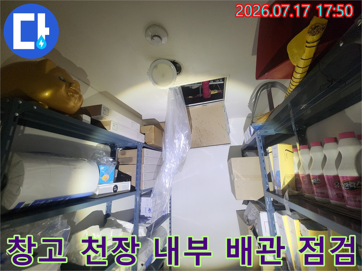 짐이 적재된 창고의 천장 부분과 누수 확인을 위한 점검구-작업 사진