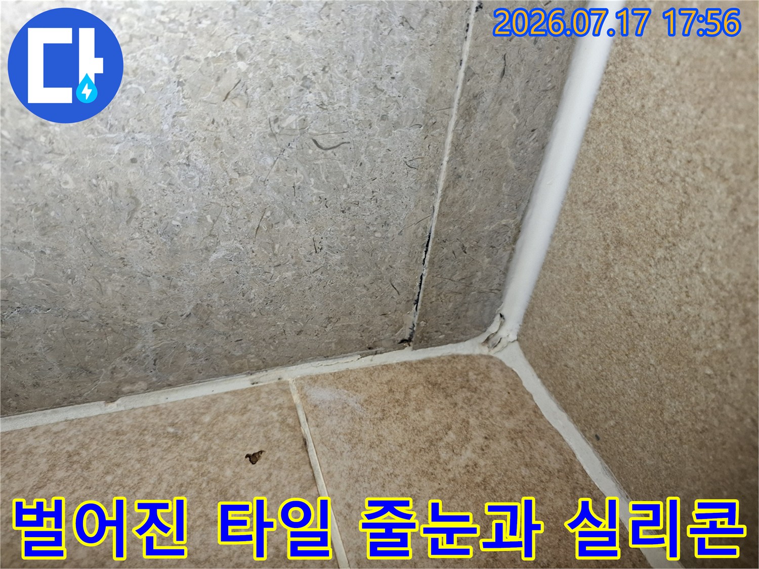 베이지색 욕실 타일의 모서리 접합 부위가 오염되고 틈새가 발생한 모습