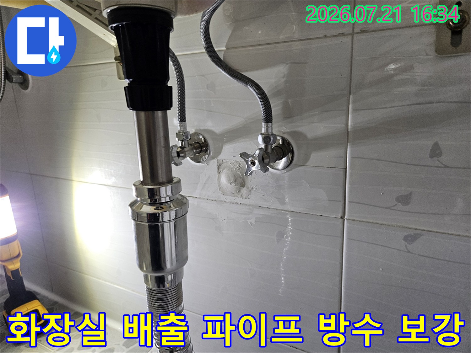 금속제 수직관과 세면대용 호스가 연결된 화장실 하부 설비 점검