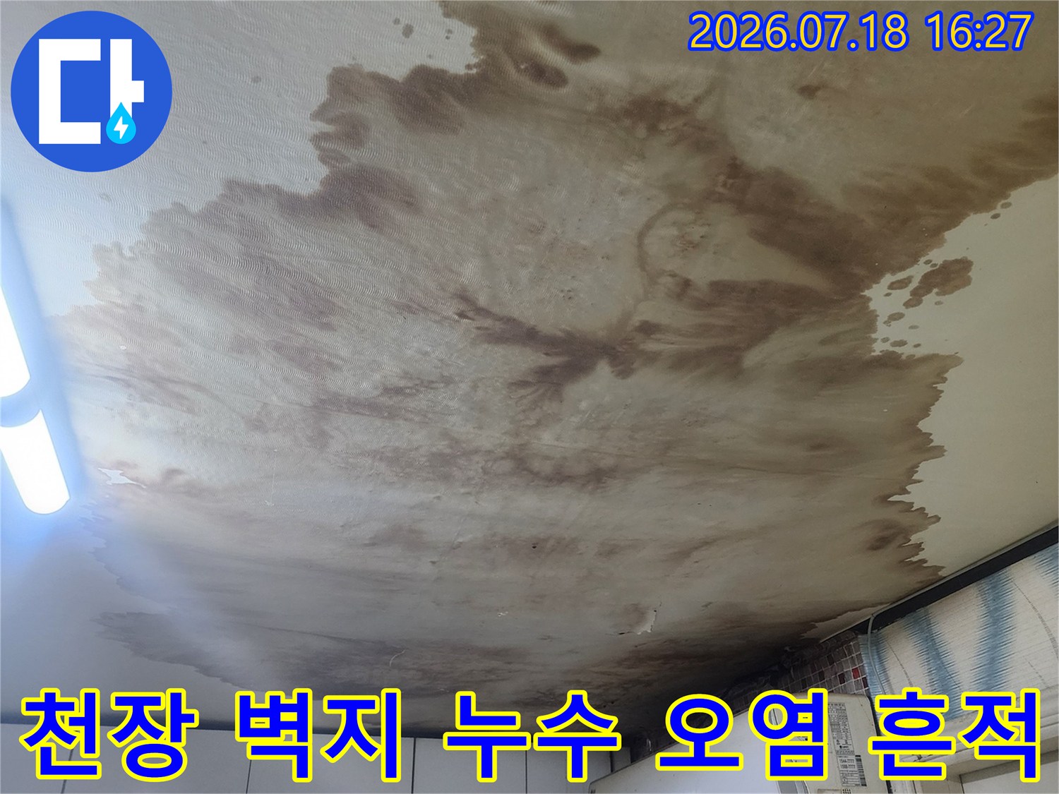 흰색 천장 벽지에 갈색으로 넓게 퍼진 누수 얼룩과 곰팡이 흔적-에어컨 설치 부근