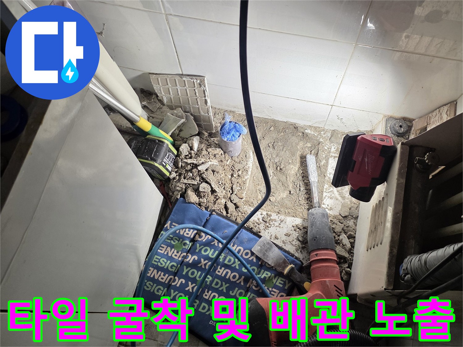 전동 드릴을 사용하여 바닥 타일을 파쇄하여 배관을 드러낸 현장