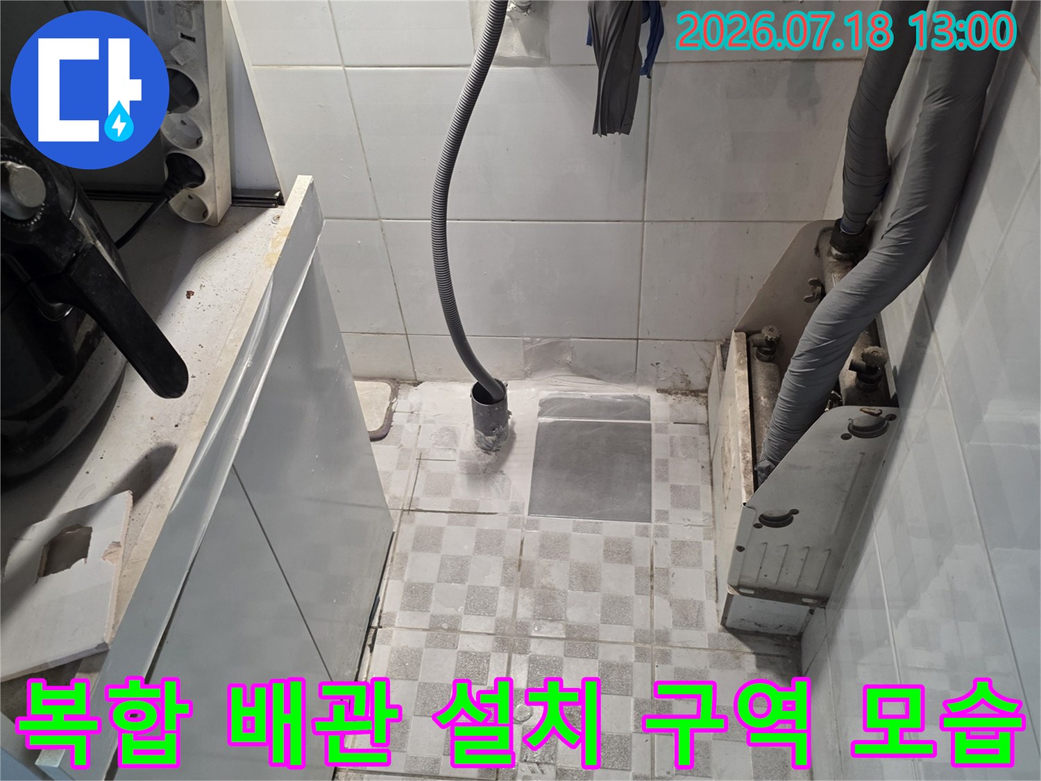 흰색 타일 벽면에 회색 보온재 관과 노란색 호스가 복잡하게 배치된 모습