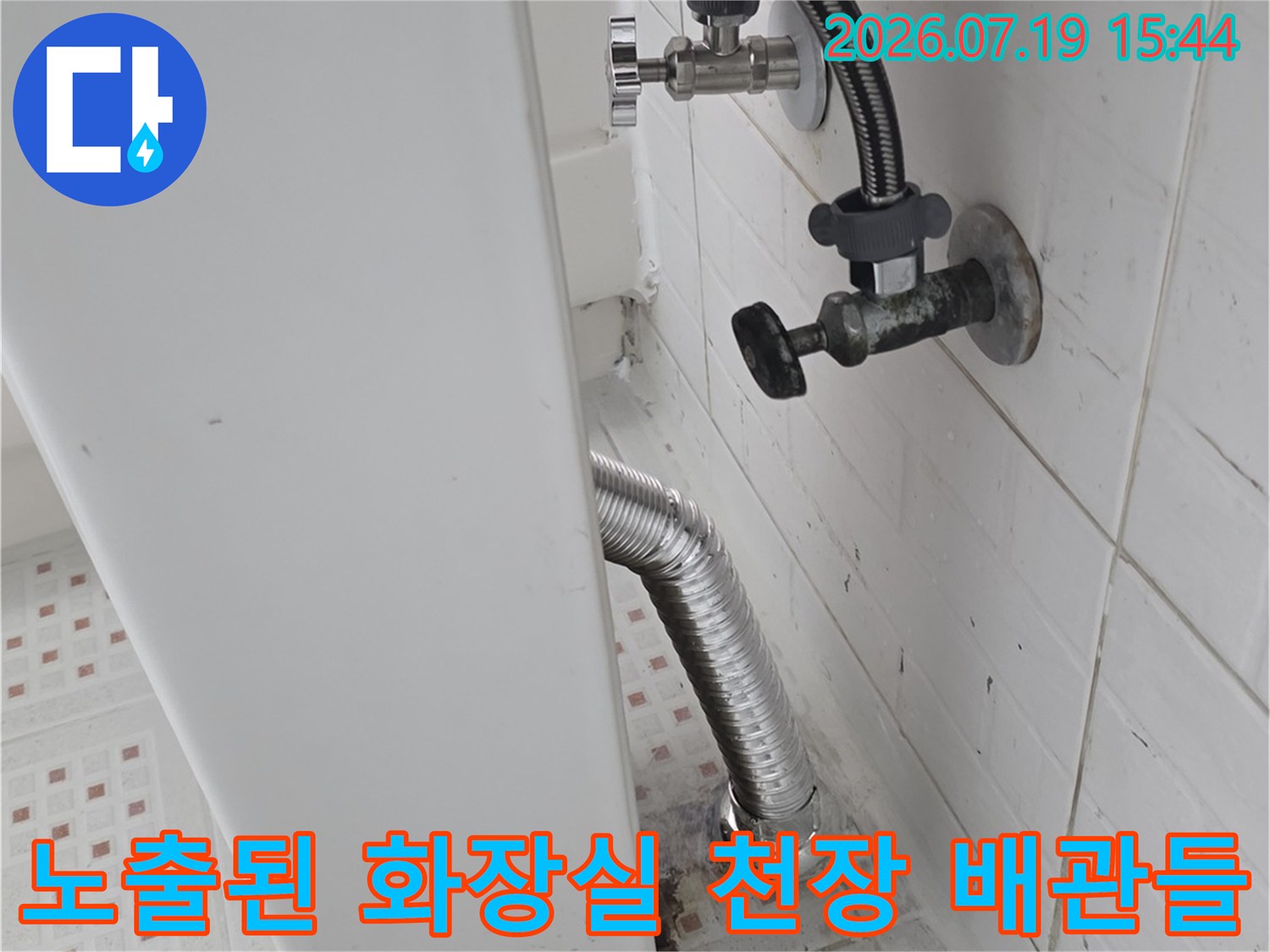 천장-마감재에-고정된-은색-금속제-배수-배관과-연결-피팅