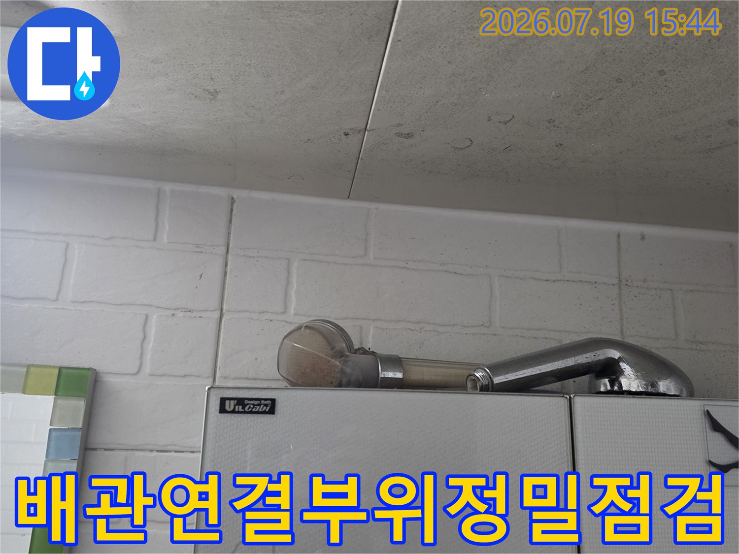 천장 상단에 배치된 회색빛의 굴절된 배관과 주변 타일 벽면 모습