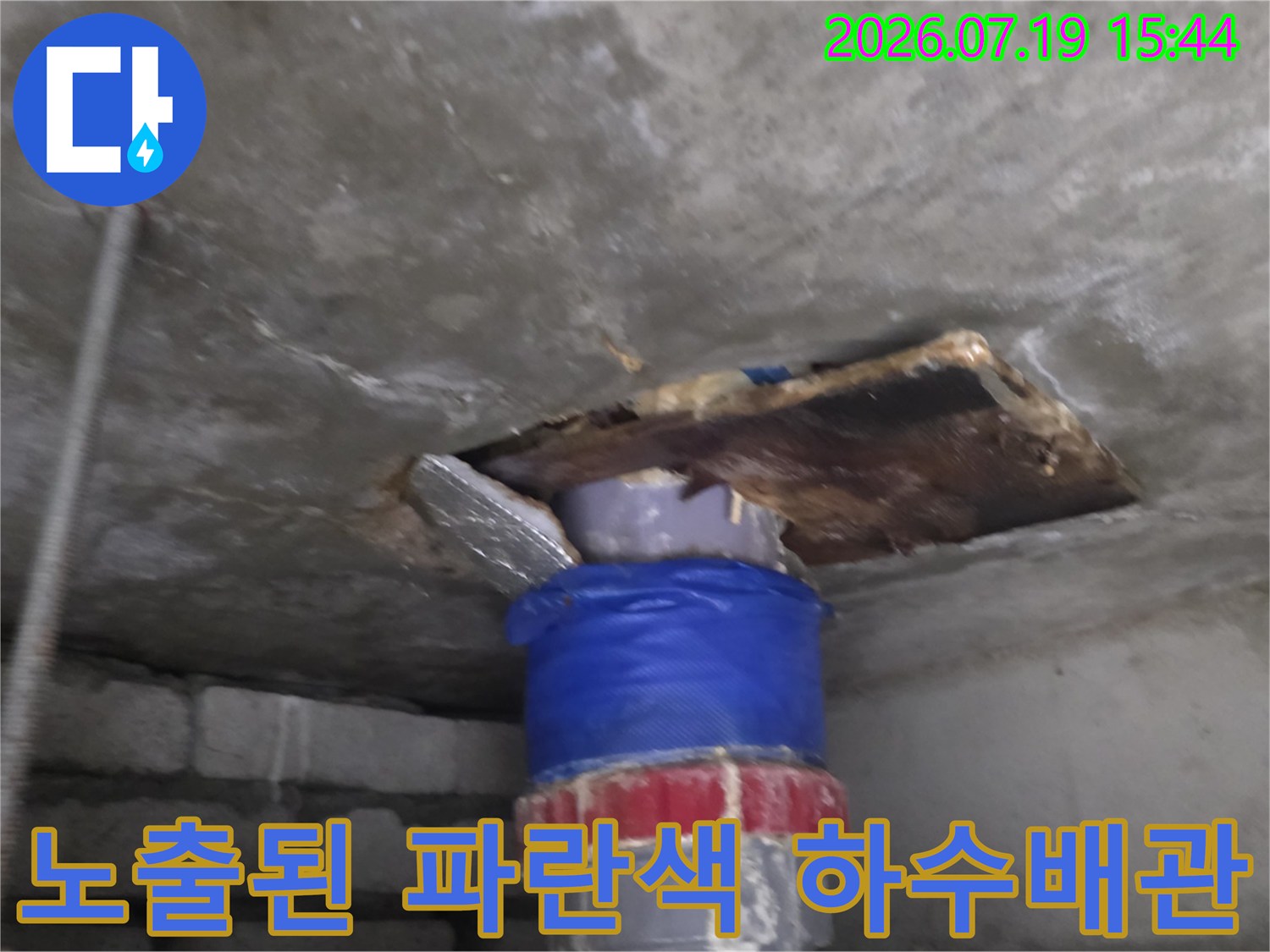 콘크리트 천장 틈새로 돌출되어 있는 파란색 테이핑 처리된 배관의 외관