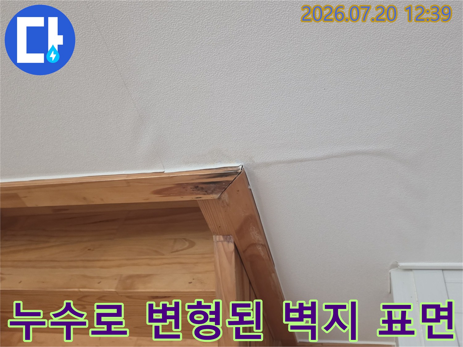 나무 선반 위쪽의 도배지가 습기를 흡수하여 볼록하게 튀어나온 사진