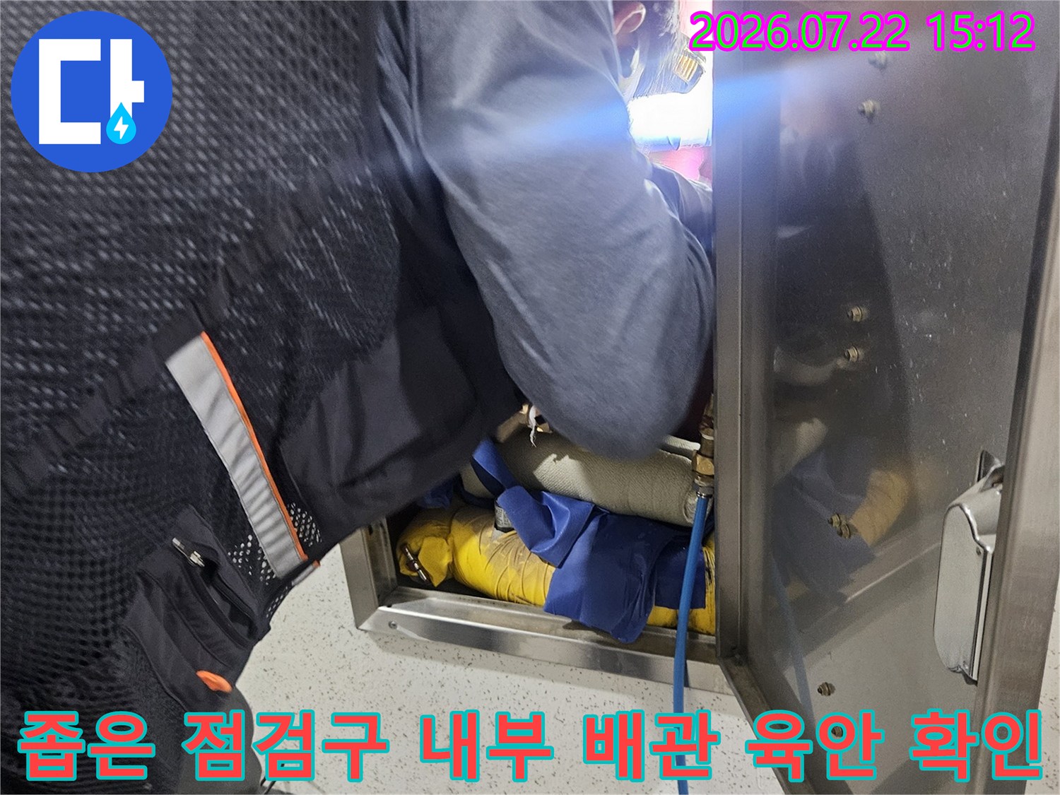 금속 커버를 열어젖히고 천장 속 배관 연결 상태를 진단하는 작업자 사진