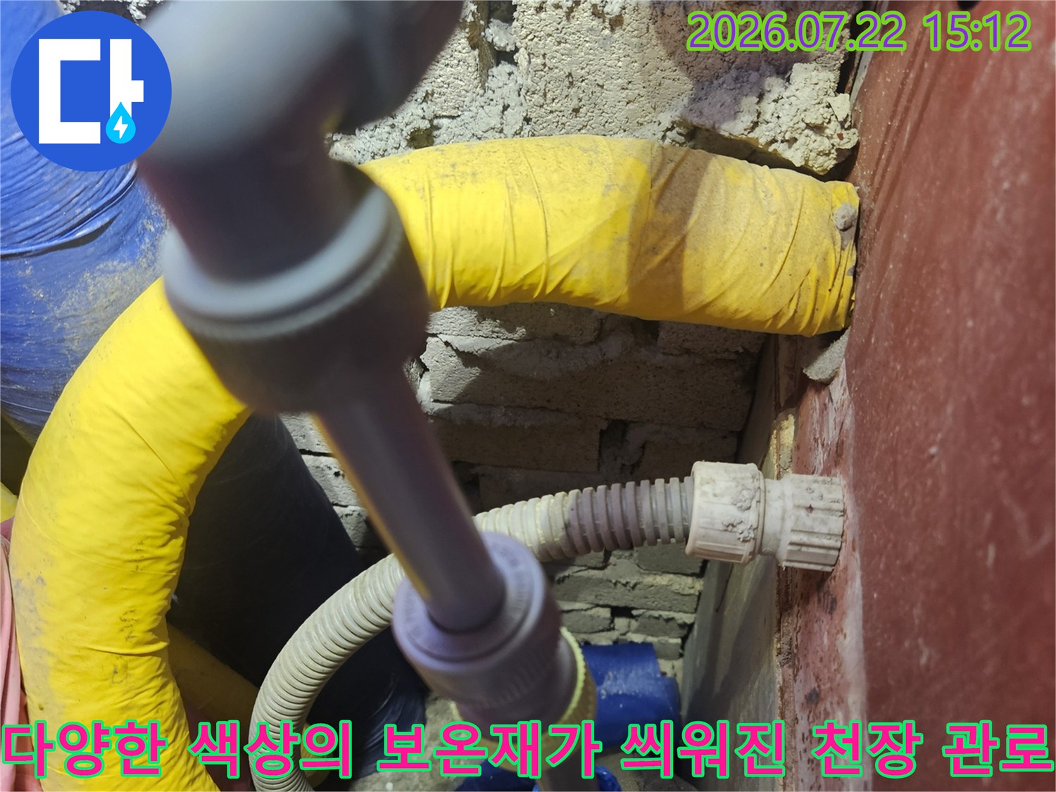 노란색-및-파란색-보온재와-회색-배관이-설치된-화장실-천장-내부-전경