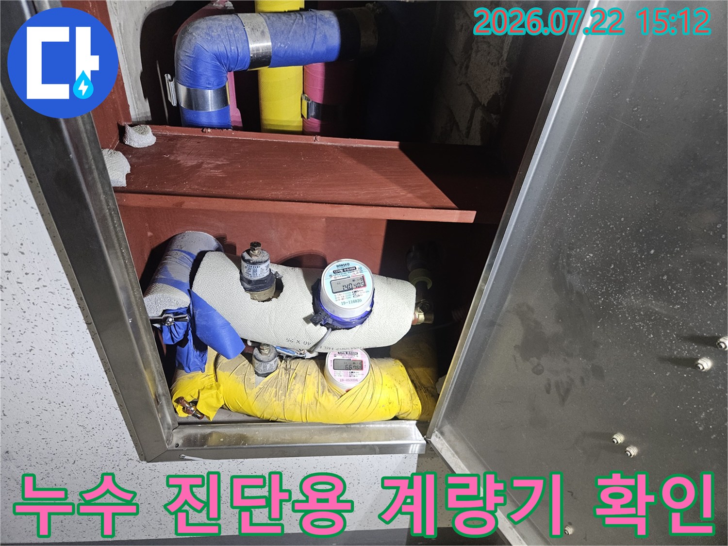점검구 내부의 파란색과 노란색 보온재 배관 및 설치된 수도 계량기 모습