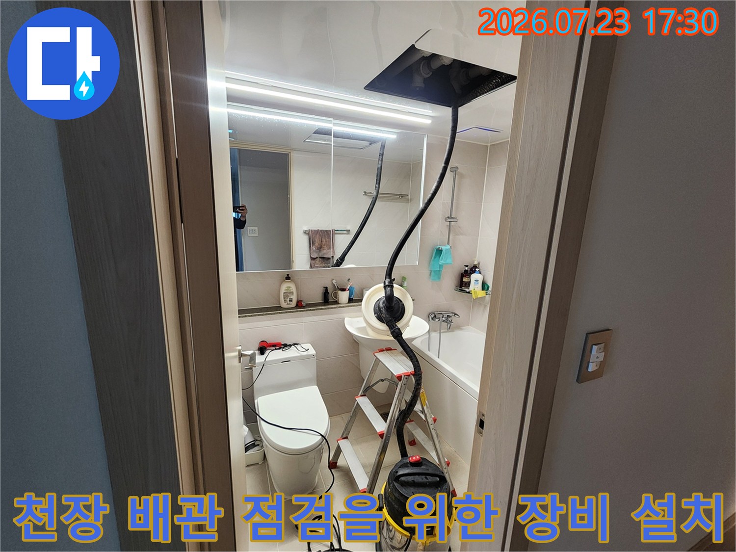 화장실 내부에 배치된 사다리와 집진기 그리고 천장에 고정된 검은색 작업용 패널