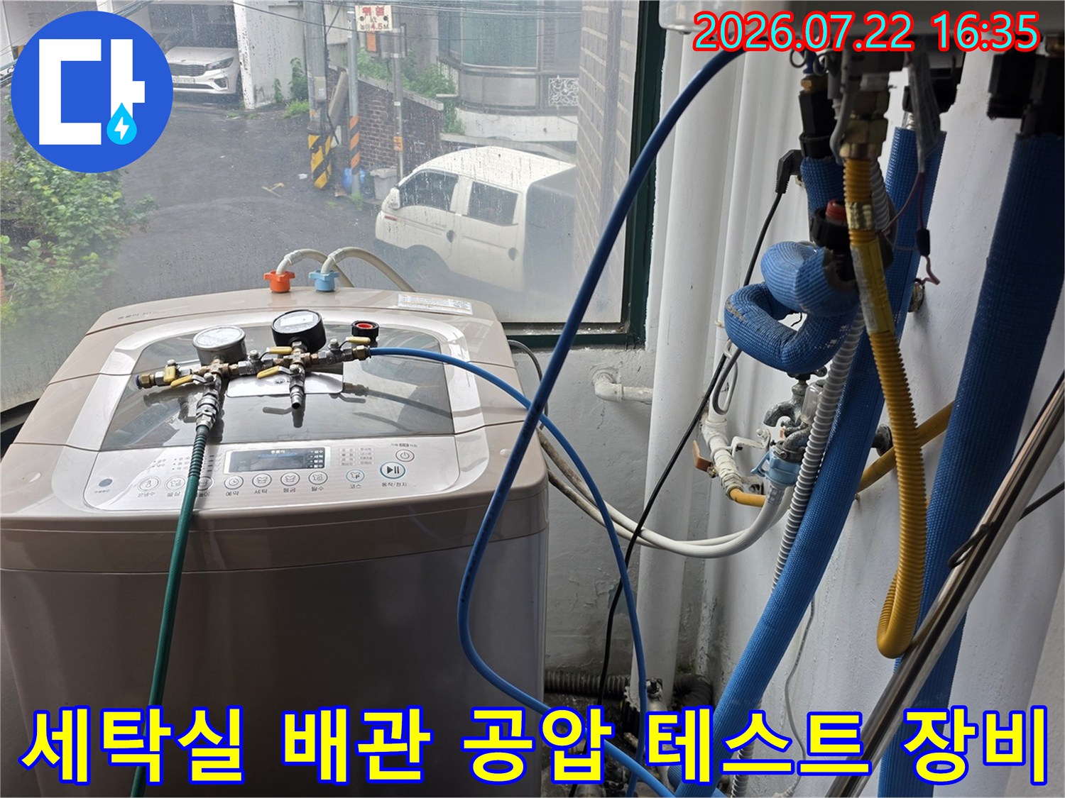 세탁기 위에 설치된 정밀 공압 측정 장비와 파란색 연결 호스-누수 탐지 과정