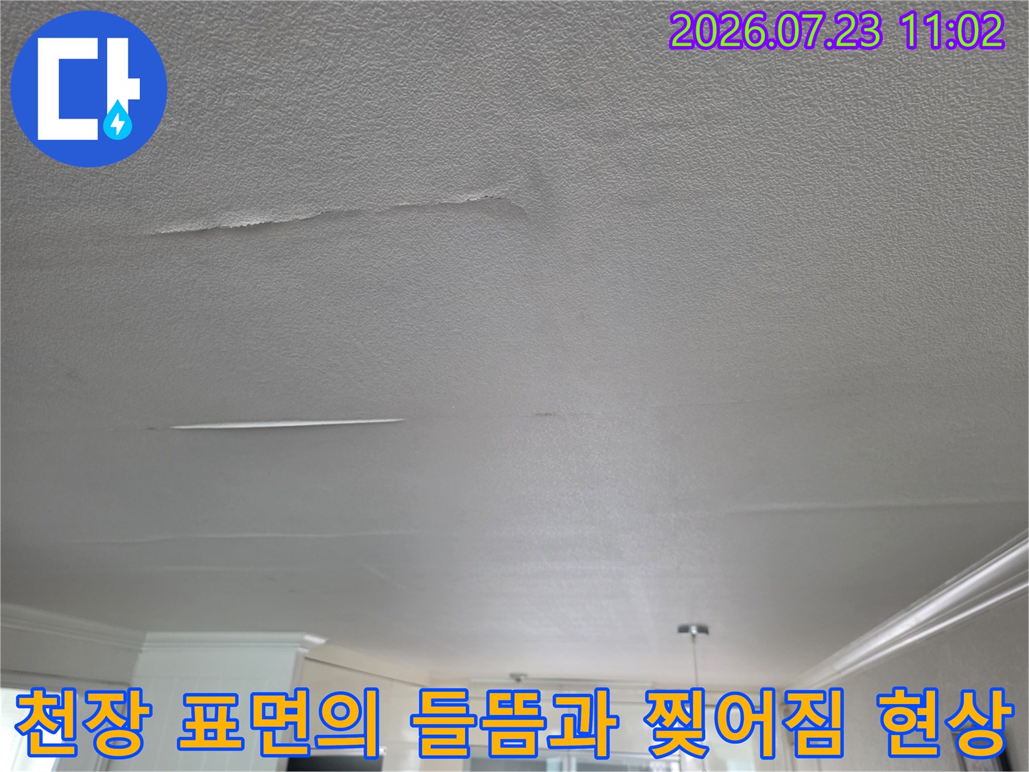 누수로 인해 거실 천장의 흰색 마감재가 부분적으로 들떠 있고 가늘게 갈라진 모습