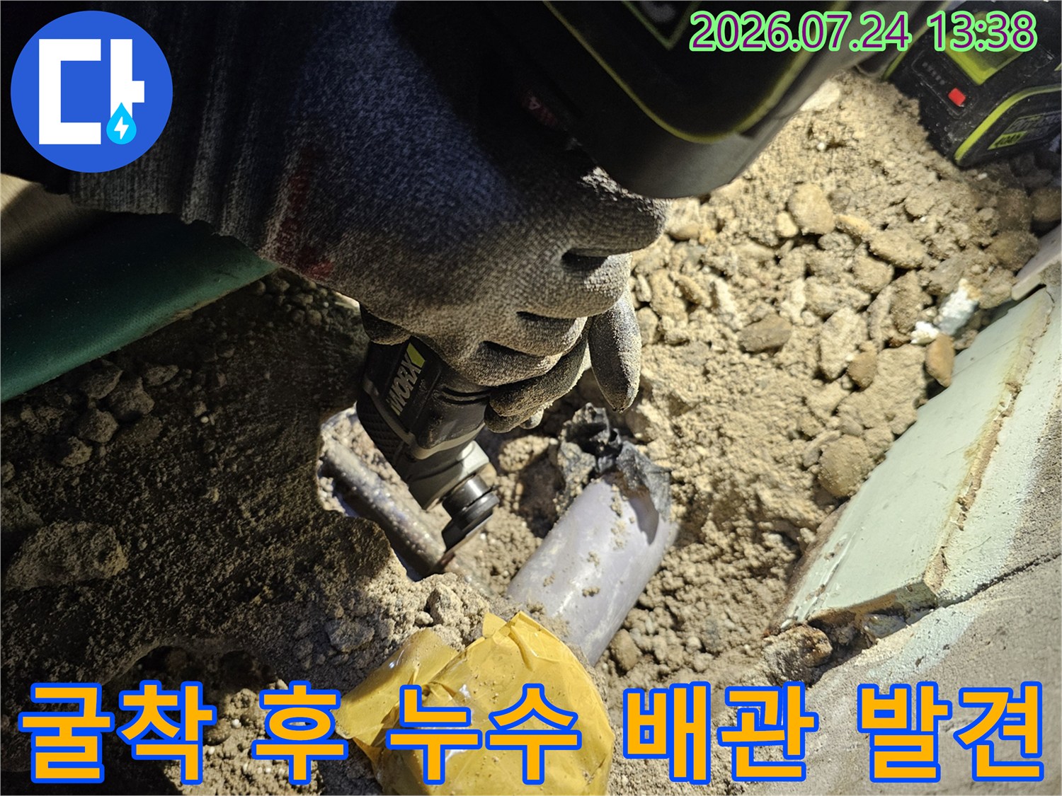 바닥을 파내어 드러난 부식된 수도 배관과 작업자의 손-전동공구 모습