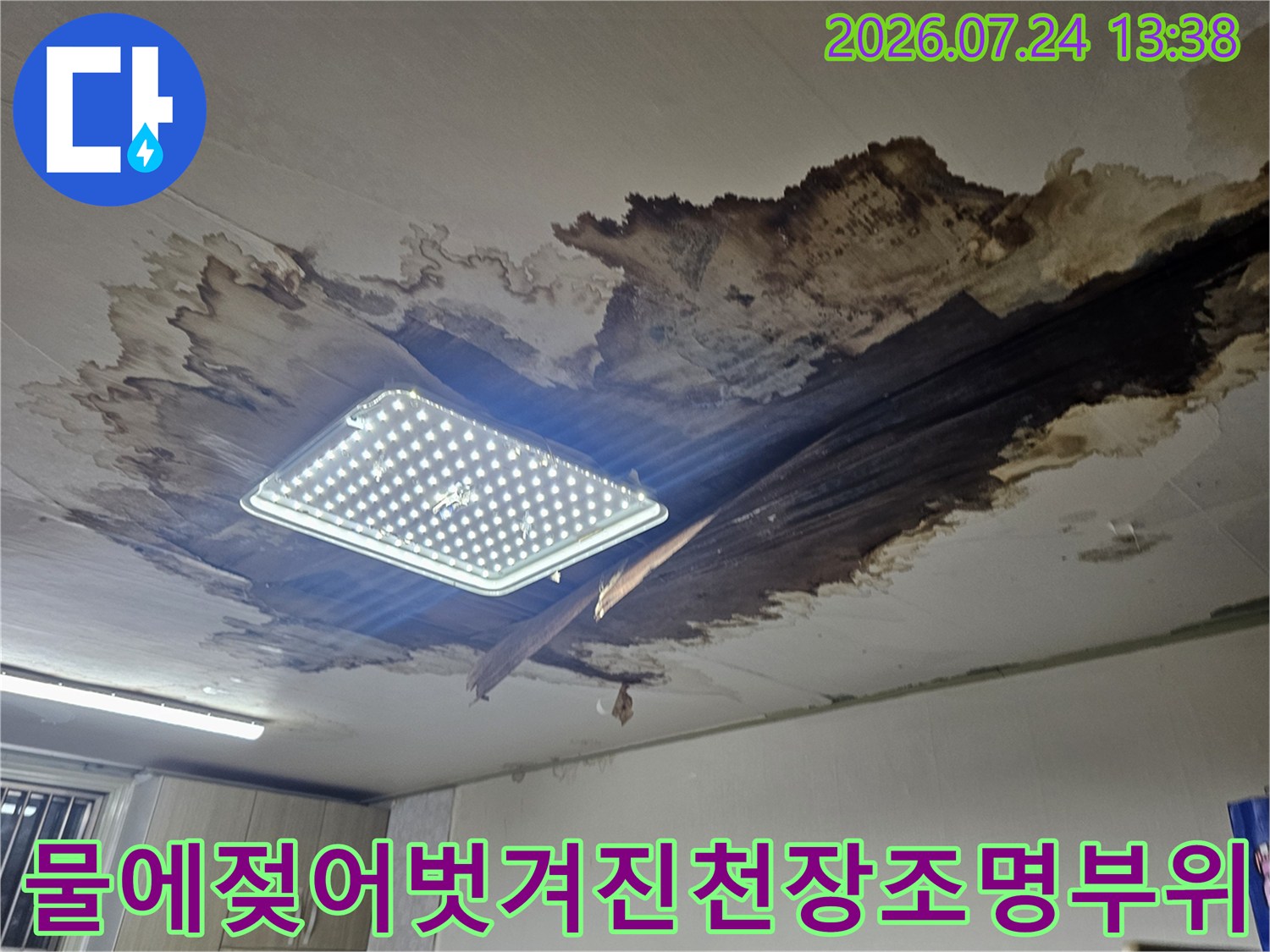 천장 조명 주변의 마감재가 물에 젖어 검게 변색되고 벗겨져 있는 모습