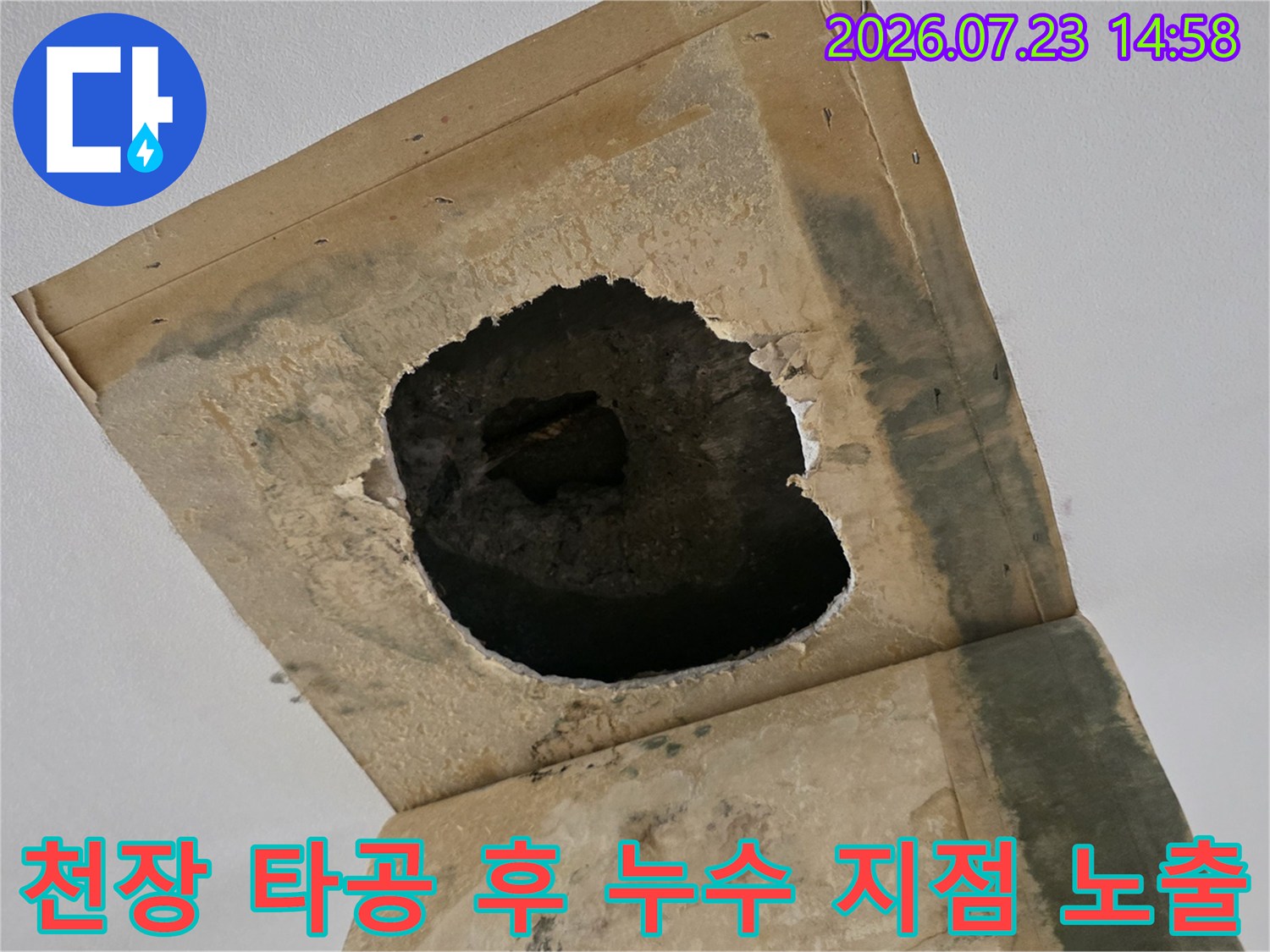 천장의 사각형 마감재 중앙에 구멍을 내어 내부의 젖은 콘크리트와 배관 부위를 촬영한 사진