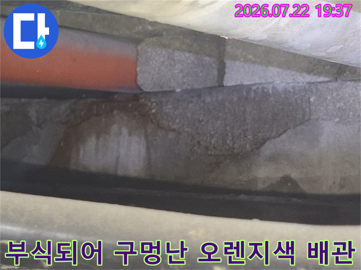 천장 내부에서 발견된 부식된 오렌지색-배관과 주변의 물 얼룩 모습