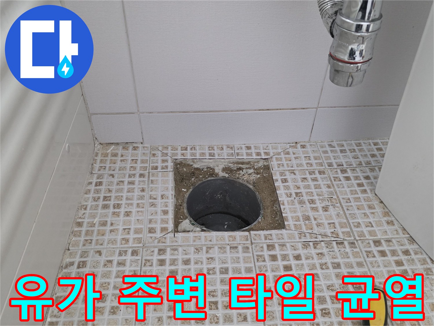 배수구 주변의 깨진 타일과 노출된 배관 입구